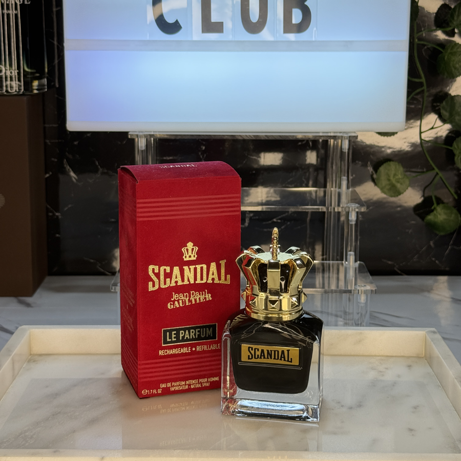 Jean Paul Gaultier Scandal Le Parfum — frasco original sobre superficie negra reflectante con fondo carbón, Parfaria Club