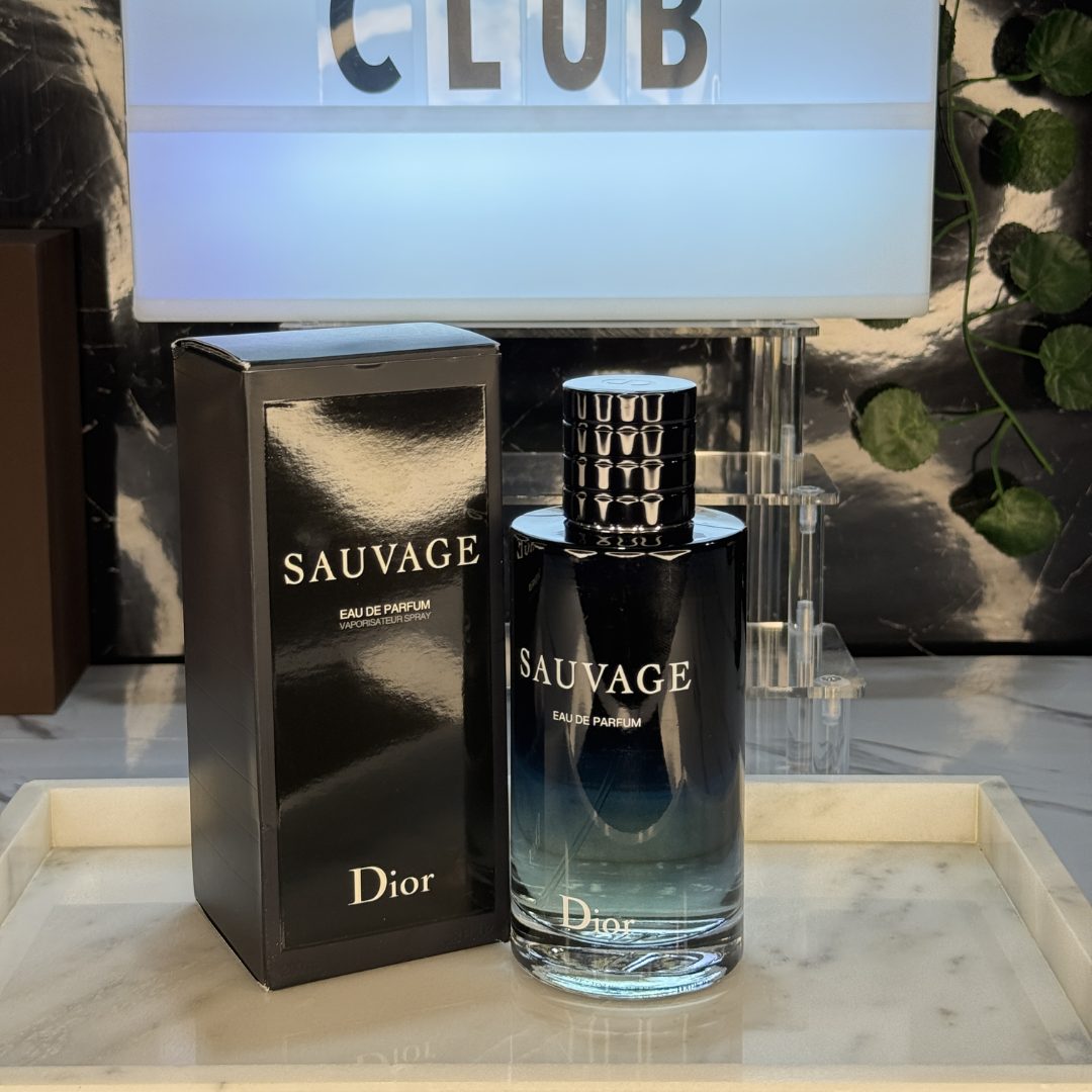 Dior Sauvage EDP — frasco original sobre superficie negra reflectante con fondo carbón, Parfaria Club