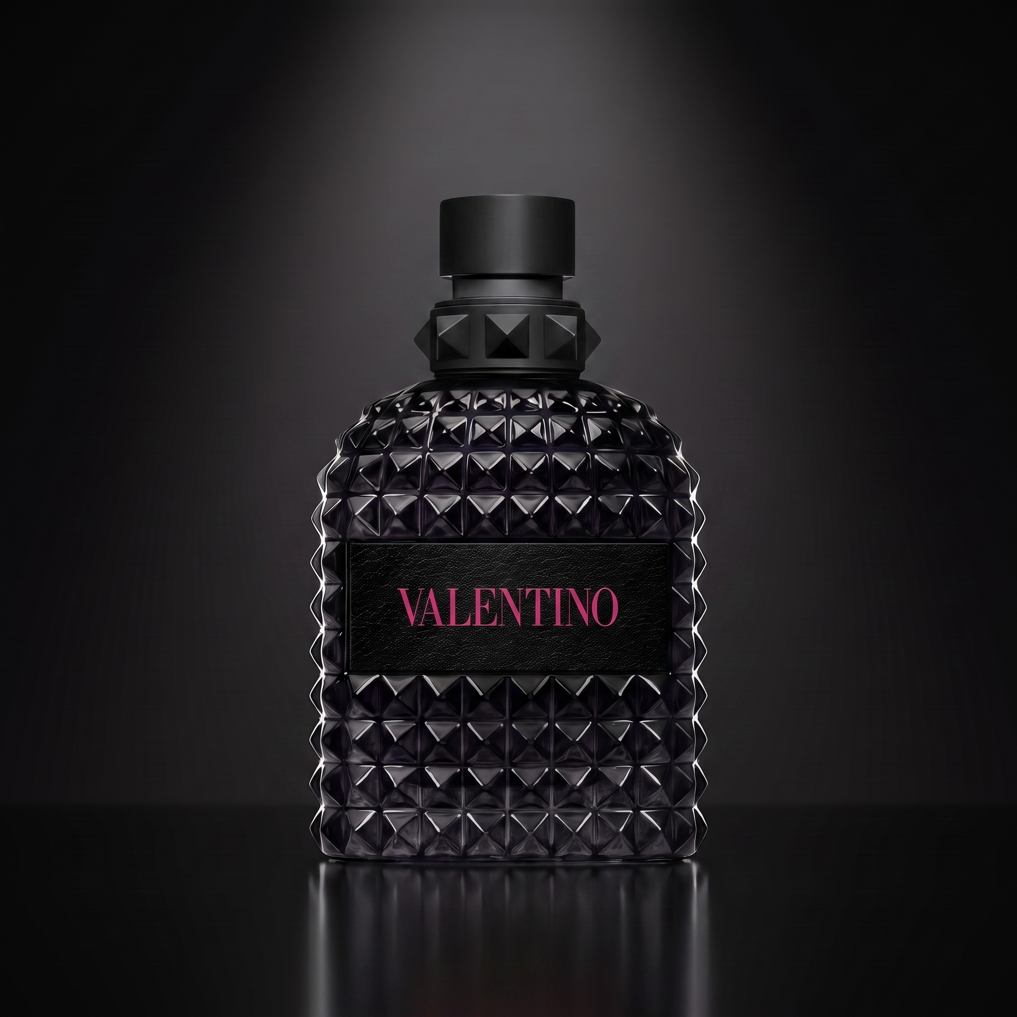 Valentino Born in Roma Extradose — frasco sobre superficie negra reflectante con fondo carbón